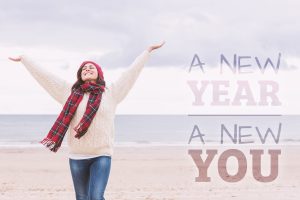 Woman in warm clothing stretching arms on beach against new year new you