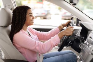 Side view profile portrait of joyful African American woman driving car